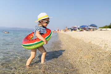 Toddler with watermelon float on beach