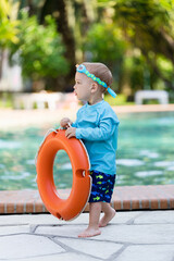 Toddler with lifebuoy near swimming pool