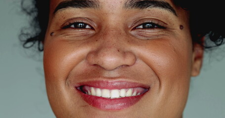 One happy young black Brazilian woman of African descent smiling at camera in tight macro close-up...