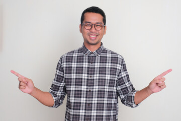 Adult Asian man smiling at the camera with hands pointing to the left and right