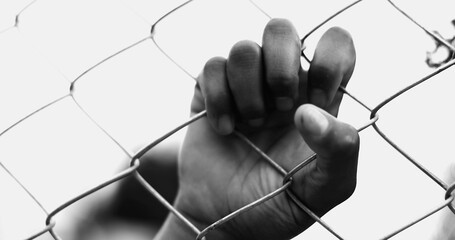 One Confined young black woman leaning on metal fence closing and opening eyes while hand holds on...