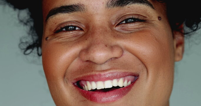 One happy young black Brazilian woman of African descent smiling at camera in tight macro close-up facial detail smile with friendly demeanor