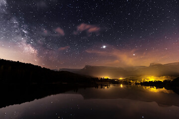 Night view of the Maroño reservoir, Alava, with the starry sky, the Milky Way and Sierra Salvada reflected in the water of the reservoir © patxi