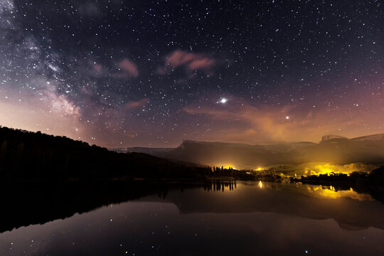 Night view of the Maro&ntilde;o reservoir, Alava, with the starry sky, the Milky Way and Sierra Salvada reflected in the water of the reservoir