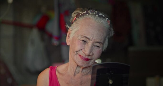 Asian woman who is an elderly person with a good mood who love to put on makeup and dress up all the time.