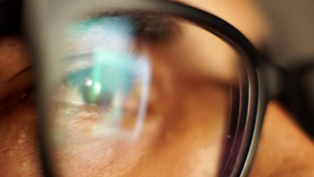 Macro closeup of eyes with eyeglasses looking at phone.