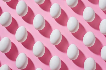 Tuinposter Row of white eggs arranged neatly on bright pink background, minimalist concept for Easter or healthy eating theme © SHOTPRIME STUDIO