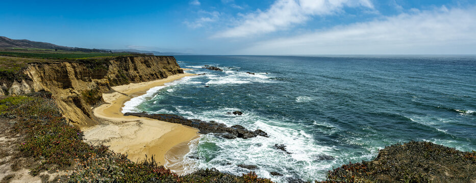 Panorama of the Pacific ocean on sandy Cowell Ranch State beach surrounded by sea cliffs, rocky headlands on sunny day in San Mateo County, California