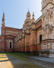Fototapeta na wymiar Left side view of Certosa di Pavia monastery, historical monumental complex that includes a monastery and a sanctuary. green court and a church, Pavia, Italy.