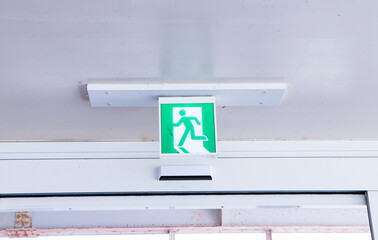 Fire exit green emergency exit signs hanging on ceiling, exit door. Warning plate with running man...