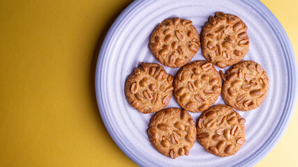 Peanut cookies lies on a blue plate. Plate on a yellow background. negative space. Place for text. Flatlay. top view