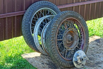 four rusty iron wheels with spokes and black rubber tires, discarded wheels from a retro motorcycle...