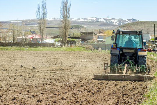 A farmer tilling the soil in spring with a tractor, prepping for a new season of growth. This image depicts the essence of agriculture