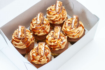 Peanut butter cupcakes with vanilla cream cheese frosting and salted caramel on top, png. Beautiful box with dessert