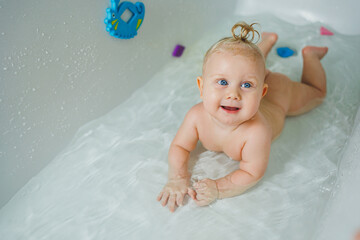 A little boy of 6 months with a ponytail on his hair is bathing in the bathroom. Bathing a baby....