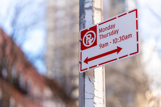 A weathered street sign stands tall, its bold red and white letters declaring "No Parking"