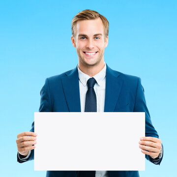 Businessman show white paper signboard with copyspace area, isolated blue marine background. Portrait of happy smiling confident man in business studio concept. Square image