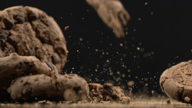 Many Chocolate chip cookies falling in super slow motion at 1000 fps with crumbs flying in the air, sugar snack impact on table surface