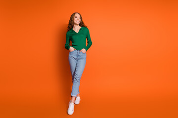 Full length photo of good mood dreamy lady dressed green shirt looking empty space isolated orange color background
