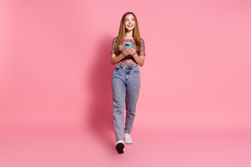 Full size photo of cheerful teen wear colorful t-shirt jeans hold smartphone look at offer empty...