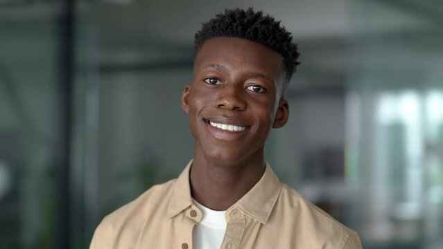 Close up portrait of young adult confident happy Black man student or company employee, smiling African guy professional entrepreneur, office worker standing indoors looking at camera.
