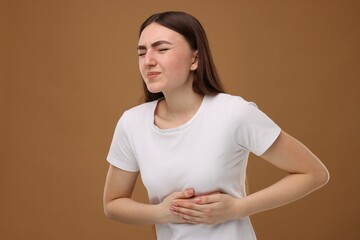 Woman having heart attack on brown background