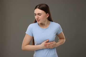 Woman having heart attack on grey background
