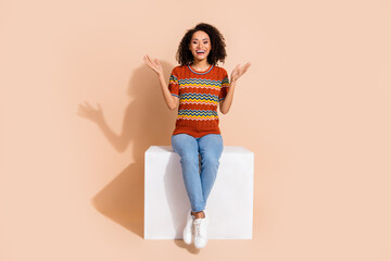 Full body photo of satisfied pretty girl dressed ornament t-shirt jeans sit on platform clap her...
