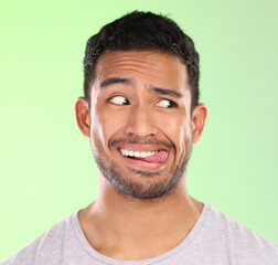 Man, play and silly in studio, tongue and goofy comic or funny face on green background. Male person, mockup space and awkward for joke or comedy, student and humor for crazy character and quirky