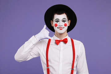 Funny mime artist showing call me gesture on purple background