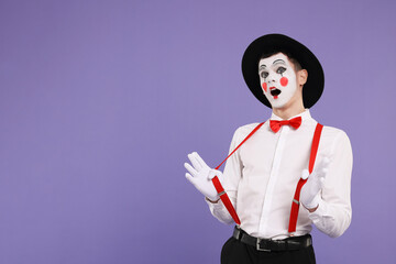 Mime artist making shocked face on purple background. Space for text