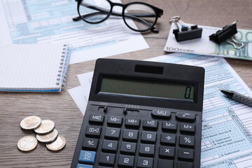 Tax accounting. Calculator, documents, stationery and glasses on wooden table, closeup