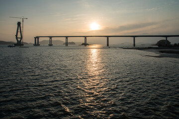 Fototapeta na wymiar constructing the bridge on the sea during sunset