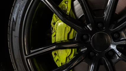 Fotobehang Close up of a black alloy wheel with a green brake caliper © Андрей Нестеров