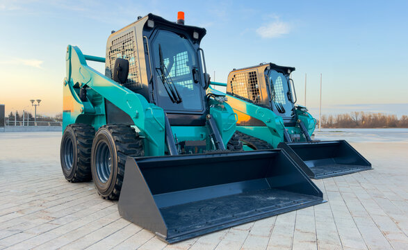 Skid steer loader for construction works. Сompact construction equipment for work in limited conditions. Road repair at construction site, city streets. Bobcat skid-steer loader for roadworks.