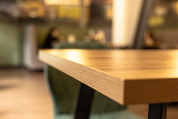 A wooden empty table in a café , defocused images of people and the cafe interior background - obrazy, fototapety, plakaty