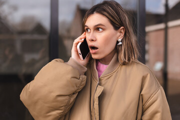 Portrait worried young woman with surprised expression talking on mobile phone, unpleasant call...