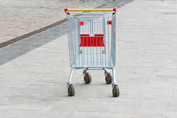 an empty shopping cart stands on the sidewalk. the concept of people lacking money for purchases....