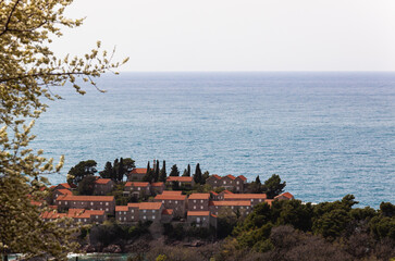 Sveti Stefan Island in the Adriatic Sea, Montenegro. Island with houses and trees. See through the trees from above. Balkans. Background - obrazy, fototapety, plakaty