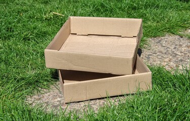 empty cardboard boxes on the path in the garden - obrazy, fototapety, plakaty