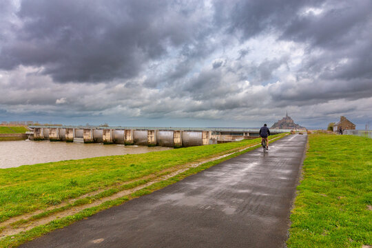 A cyclist rides along a canal in the Normandy region.