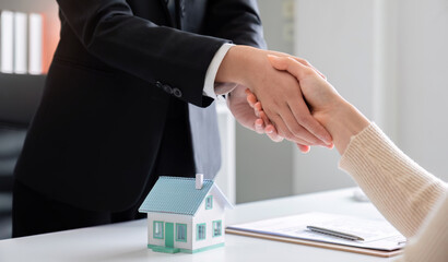 Real estate agent or realtor shakes hands with her client after making the deal in the office....