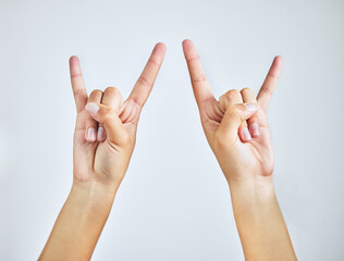 Hands, closeup and person in studio with rock and roll sign, gesture or symbol on white background....