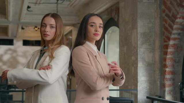 Two confident feminism strong Caucasian businesswomen girls female business women partners crossing arms in company coworkers colleagues posing in office crossed hands together partnership teamwork