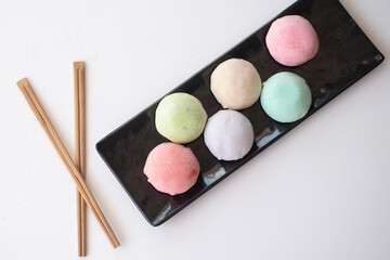 Six mochi different tastes and colors on black plate on white background. Japanese traditional frozen dessert mochi. ice cream with dough of sticky rice. fresh delicious appetizer. asian cuisine