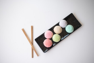 Six mochi different tastes and colors on black plate on white background. Japanese traditional frozen dessert mochi. ice cream with dough of sticky rice. fresh delicious appetizer. asian cuisine