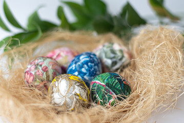 Easter colorful eggs in basket with decorative straws on light background. Spring Christian holiday of Orthodox believers.