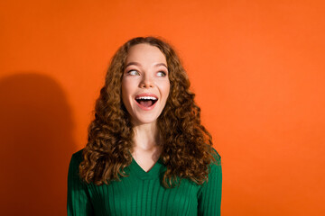 Photo of excited dreamy lady dressed green shirt looking emtpy space isolated orange color background