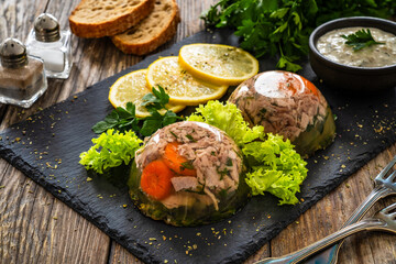 Meat in jelly, toasted bread and fresh vegetables on  wooden table
