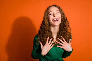 Photo of excited dreamy lady dressed green shirt arms chest laughing emtpy space isolated orange color background